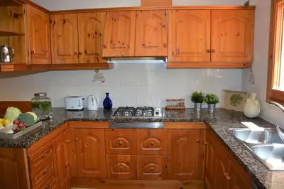 a kitchen with wooden cabinets and granite counter tops at Villa Sitges Colibri at 10 min Walk Beaches - Center City Amaizing Garden Pool XXL Private Tenis Piste in Vilanova i la Geltrú