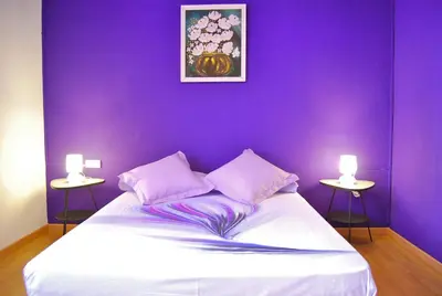 a purple bedroom with a white bed with two tables at Clot MiraBarna Apartments in Barcelona