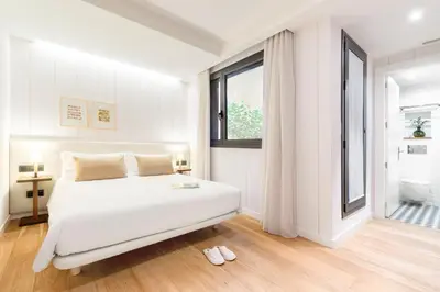a white bedroom with a bed and a window at Casa Bella Gracia by Aspasios in Barcelona
