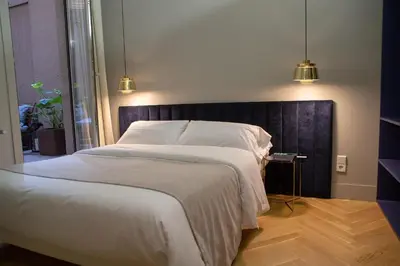 a white bed with a flat screen tv on a wall at BUHO Boutique Rooms in Barcelona