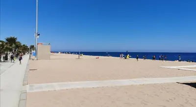 a beach with people walking on the sand and the ocean at Apartamento a 100 metros de la playa in Pineda de Mar