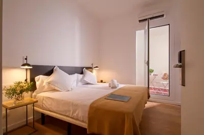 a bedroom with a large white bed and a window at Som Nit Triomf in Barcelona