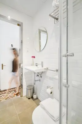 a white bathroom with a sink and a mirror at Som Nit Triomf in Barcelona
