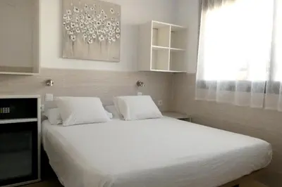 a bedroom with a bed with white sheets and a window at Hostal House in Barcelona