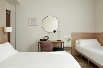 a hotel room with two beds and a mirror at Hostal Centric in Barcelona