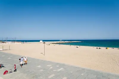 a group of people walking on a beach at Basic Platja in Barcelona