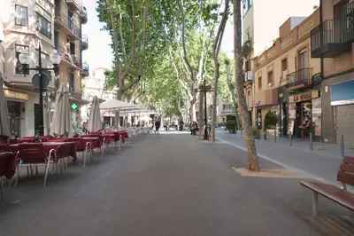 an empty street with tables and chairs in a city at Basic Platja in Barcelona
