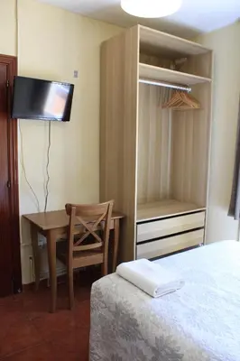 a bedroom with a bed and a table and a desk at Hostal La Romànica in Sabadell