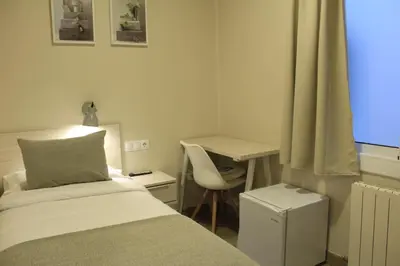 two beds in a room with lights on the wall at Hostal La Romànica in Sabadell