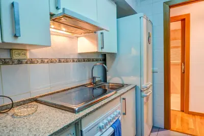 a kitchen with a sink and a refrigerator at Aire Apartment by Hello Homes Sitges in Sitges