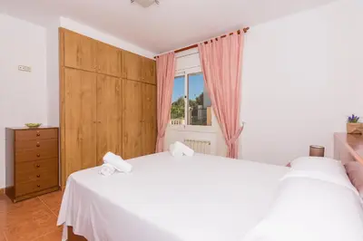 a bedroom with a white bed and a window at HomeHolidaysRentals Aube in Sant Cebrià de Vallalta