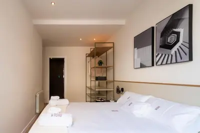 a bedroom with a bed with three pillows and a tv at Petit Luxe Tobella Baixos in Terrassa