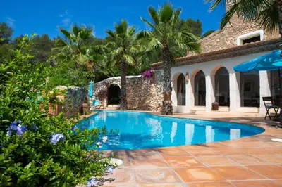 a swimming pool in front of a house with palm trees at Casa Los Arcos at Masia Nur Sitges, Adults only in Canyelles