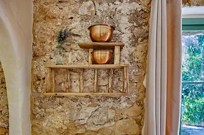 a stone wall with wooden shelves on a wall at Casa Marqués at Masia Nur Sitges, Adults only in Canyelles