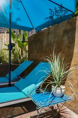 a blue chair with a potted plant and an umbrella at Casa Granada at Masia Nur Sitges, with private pool and adults only in Canyelles
