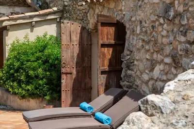a wooden door with a bench in front of a stone wall at Villa Hermosa at Masia Nur Sitges, Adults only in Canyelles