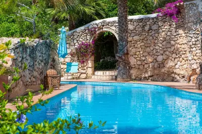 a swimming pool in front of a stone wall at Casa Azul at Masia Nur Sitges, Adults only in Canyelles