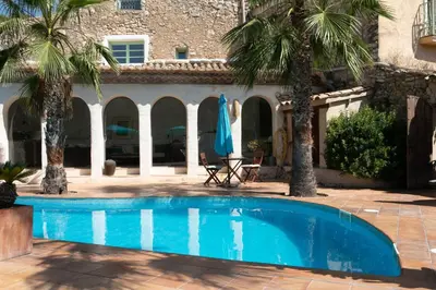 a swimming pool in front of a house with palm trees at Casa Olivo at Masia Nur Sitges, Adults only in Canyelles