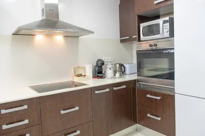 a kitchen with wooden cabinets and a microwave at Apartamento Montroig 2 in Sitges