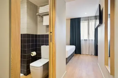 a small bathroom with a toilet and a bedroom at Hotel Brick Barcelona in Barcelona
