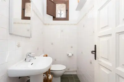 a white bathroom with a sink and a toilet at Luxury Villa El Turo in Castellví de Rosanés