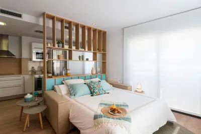 a bedroom with a large bed and a kitchen at Sitges Centre. Simply Charming in Sitges