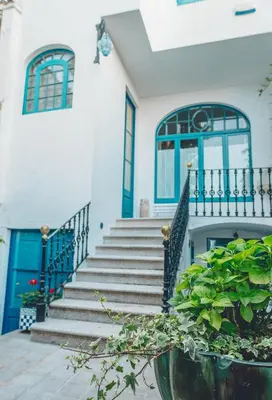 a house with blue doors and stairs with a potted plant at Casa Baulenas in Caldes d'Estrac