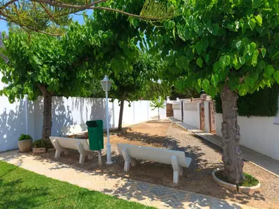 a park with two white benches under a tree at Holiday Home Katy by Interhome in Cunit