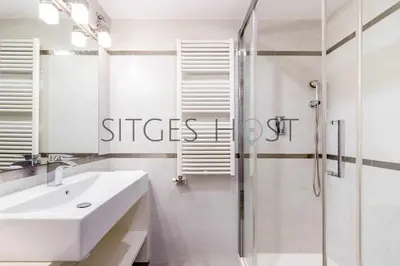 a white bathroom with a shower and a sink at A 20 metros de la playa in Sitges
