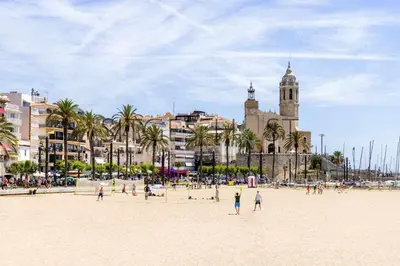 a group of people on a beach with a clock tower at A 20 metros de la playa in Sitges