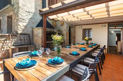 a long wooden table with blue dishes on top at 21 Sleeps Private Pool Villa & BBQ Near Barcelona in Rocafort