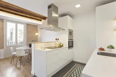 a kitchen with white cabinets and a sink and a table at Ola Living Calabria in Barcelona
