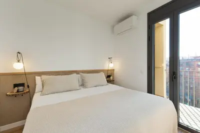a bedroom with a white bed and a large window at Ola Living Calabria in Barcelona