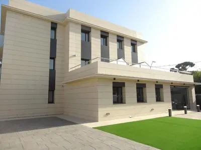 a building with a green lawn in front of it at 6 Bis HOTEL in Castelldefels
