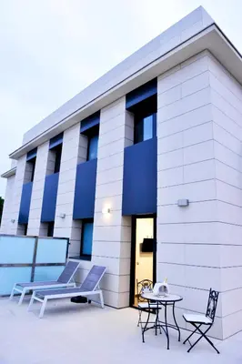 a building with chairs and a table in front of it at 6 Bis HOTEL in Castelldefels