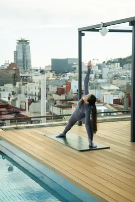 a woman doing a yoga pose on top of a rooftop at Kimpton Vividora Hotel by IHG in Barcelona
