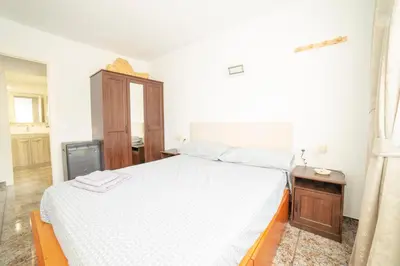 a bedroom with a white bed and a wooden cabinet at CUNIT HOME in Cunit