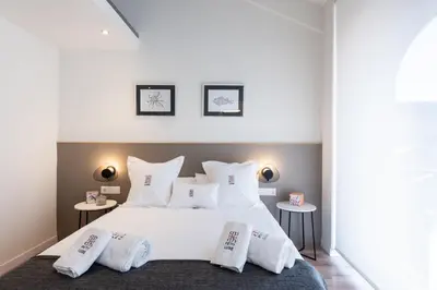 a bedroom with a large white bed with two tables at Petit Luxe Tobella Esquerra in Terrassa