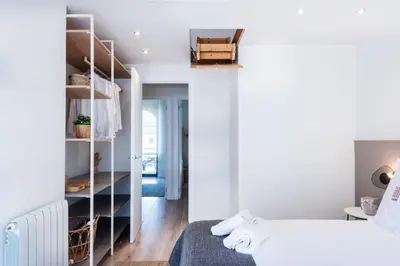 a white bedroom with a bed and a closet at Petit Luxe Tobella Esquerra in Terrassa