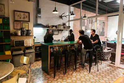 a group of people sitting at a bar in a kitchen at Pars Tailor's Hostel in Barcelona