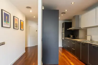a kitchen with black cabinets and a white wall at Uma Suites Passeig de Gracia 16 in Barcelona