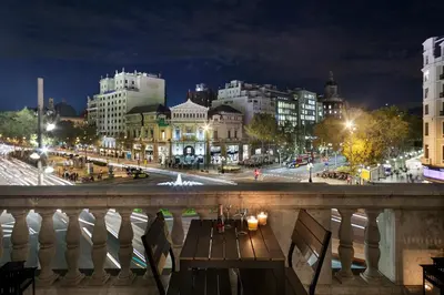 a view of a city at night from a balcony at Uma Suites Passeig de Gracia 16 in Barcelona
