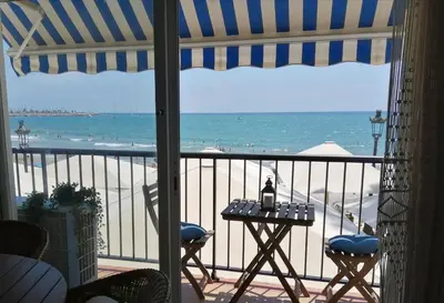 a view of the beach from a balcony with a table at Port alegre - en el corazón de Sitges in Sitges