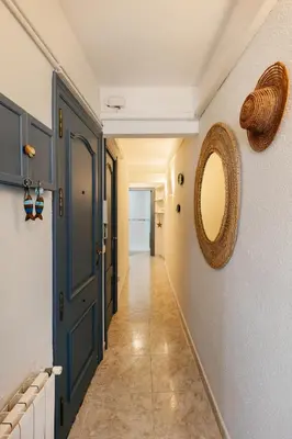a hallway with a blue door and a mirror at Port alegre - en el corazón de Sitges in Sitges