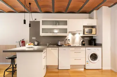 a kitchen with white cabinets and a washer and dryer at Aspasios Las Ramblas Apartments in Barcelona