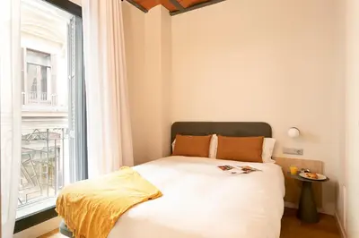 a bed in a room with a large window at Aspasios Las Ramblas Apartments in Barcelona