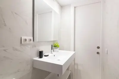 a white bathroom with a sink and a mirror at Aspasios Las Ramblas Apartments in Barcelona