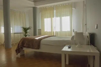 a white bedroom with a bed and a table at Monrooms Barcelona in Barcelona