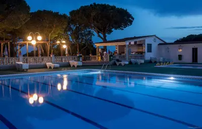 a swimming pool at night with a house at Camping Roca Grossa in Calella