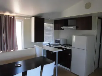 a small kitchen with a white refrigerator and a table at Camping Roca Grossa in Calella